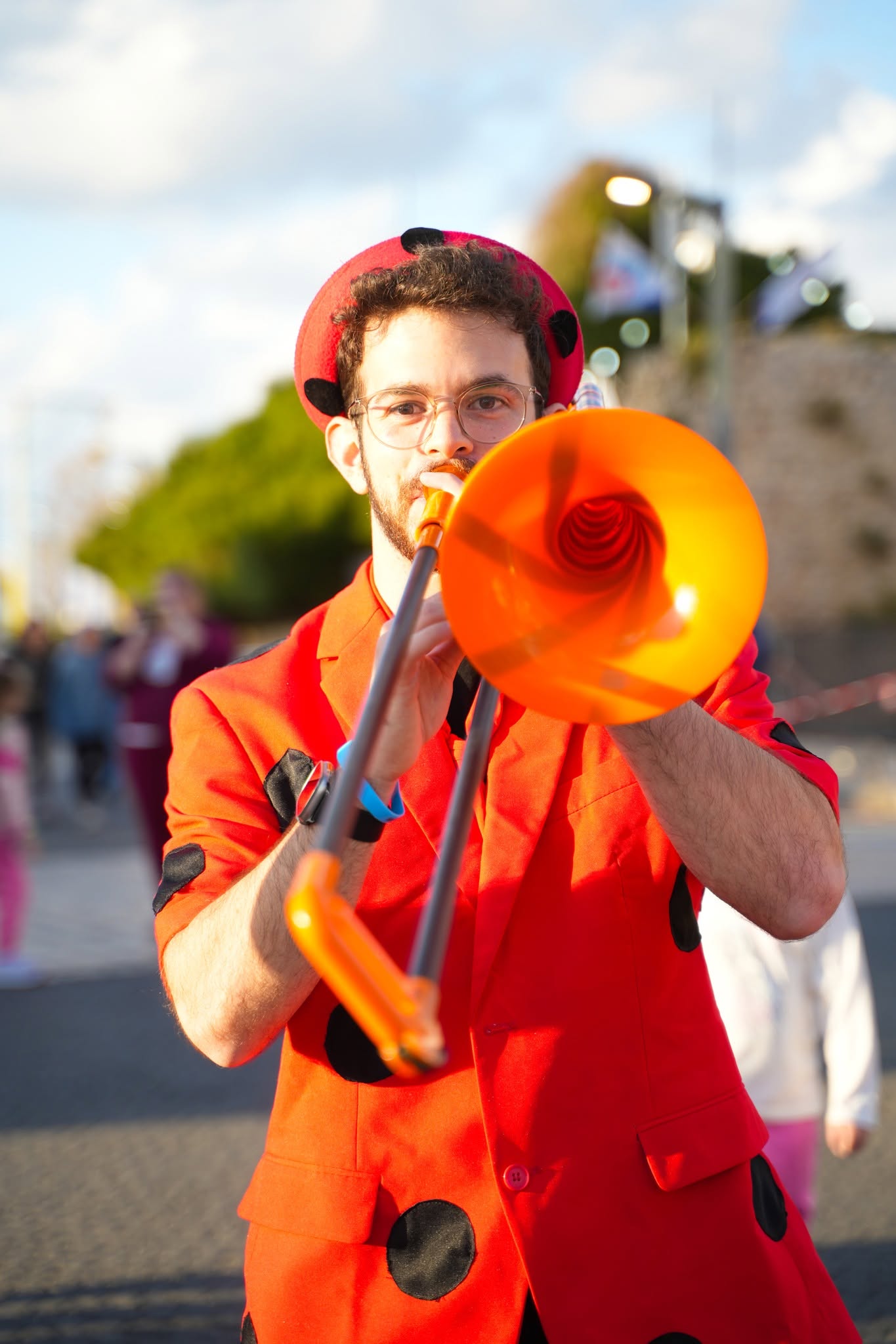 A street performer plays an orange trumpet.