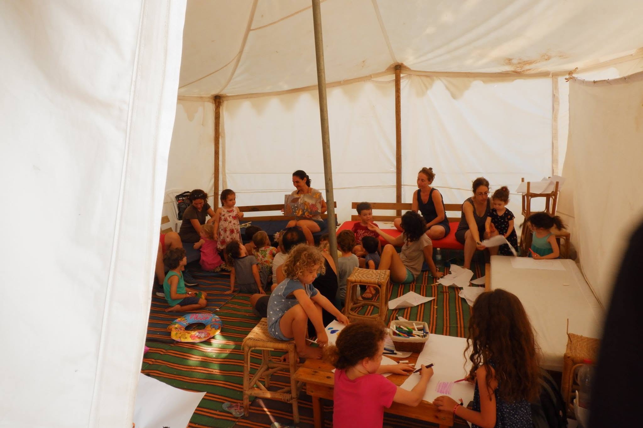 Families sit in a small circle inside an activity tent.