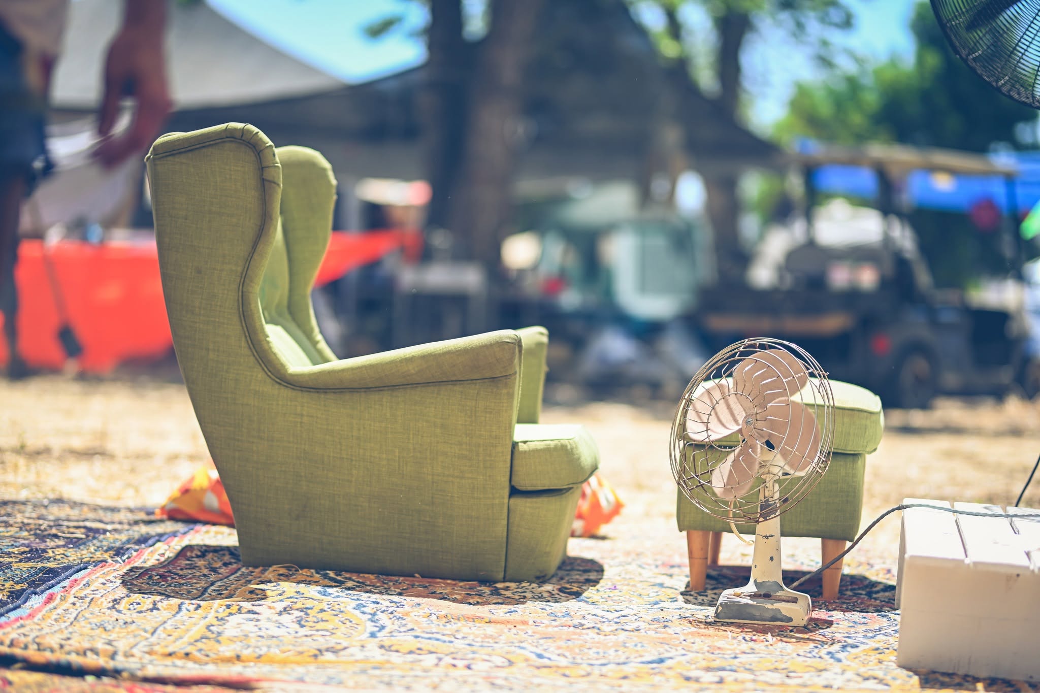 A green armchair and a small fan in an outdoor seating nook.