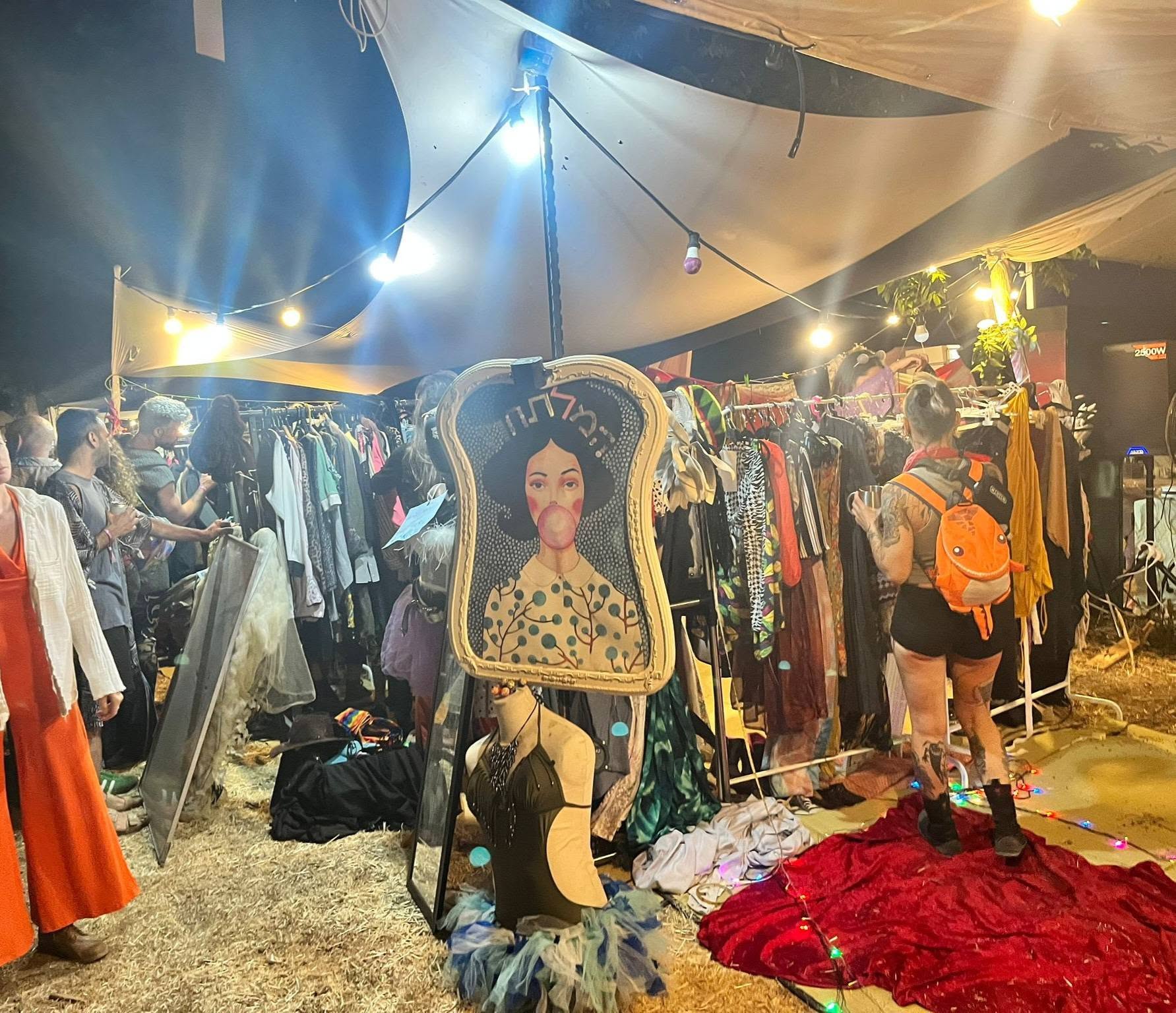Clothes and costumes hang on display inside a lit tent.