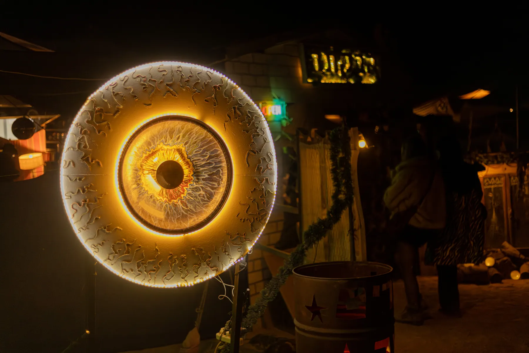 A glowing circular installation resembling a giant eye in the night market.